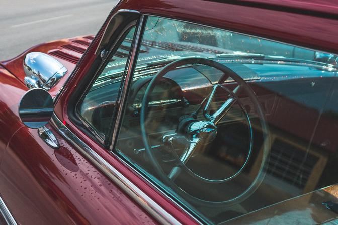 The dashboard of a red classic car, taken through the window at an angle