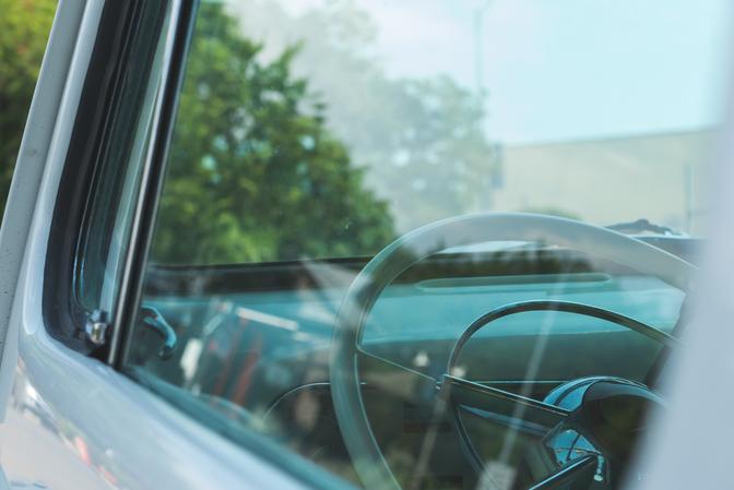 The dasbhoard of a white classic car, taken through the window